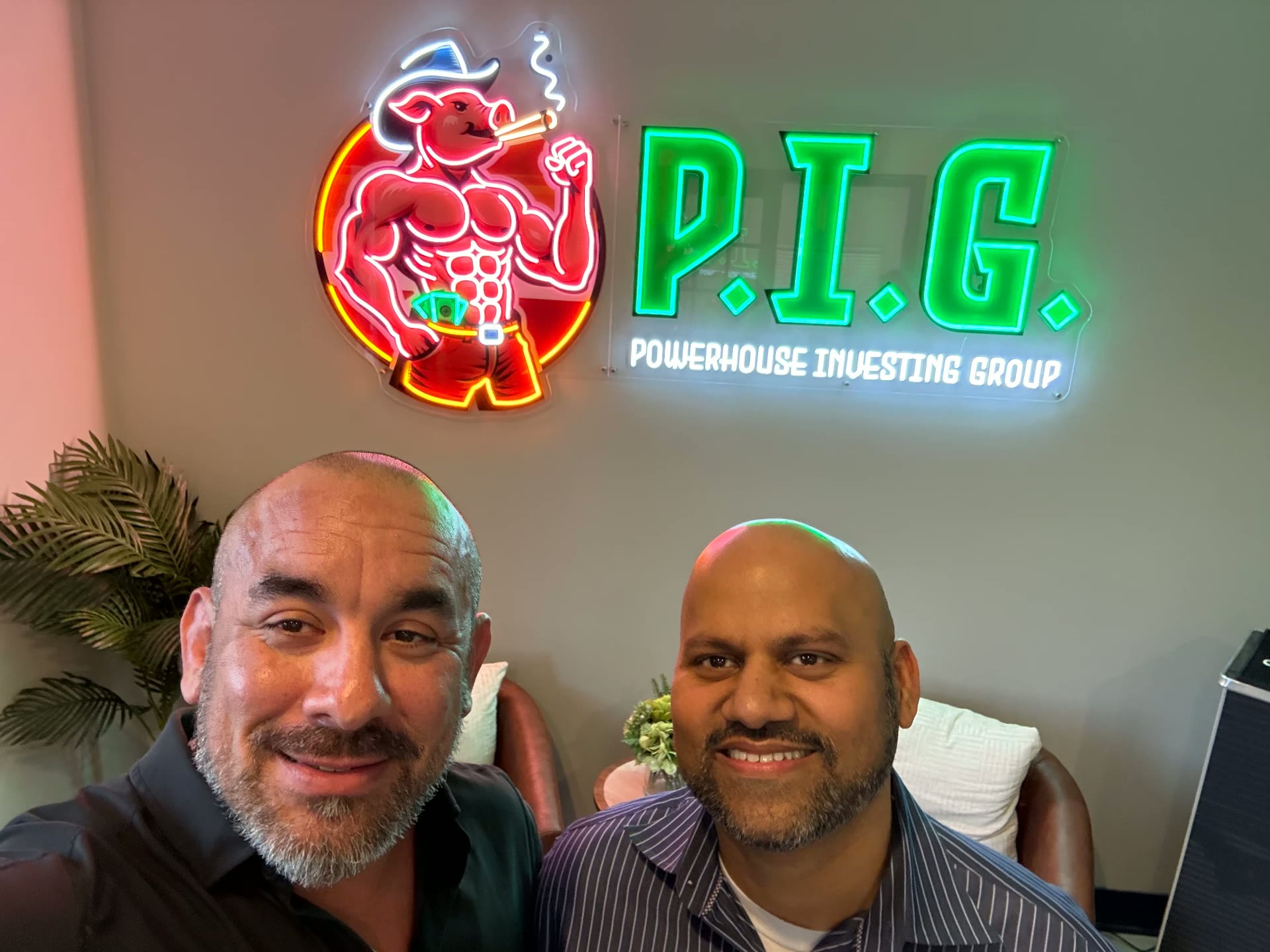 Members in front of the P.I.G. neon sign at the office